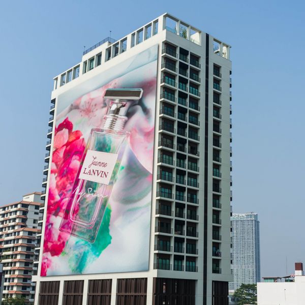 Lona microperforada calandrada en fachada con impresión UV y diseño de perfume Jeanne Lanvin. Publicidad exterior.